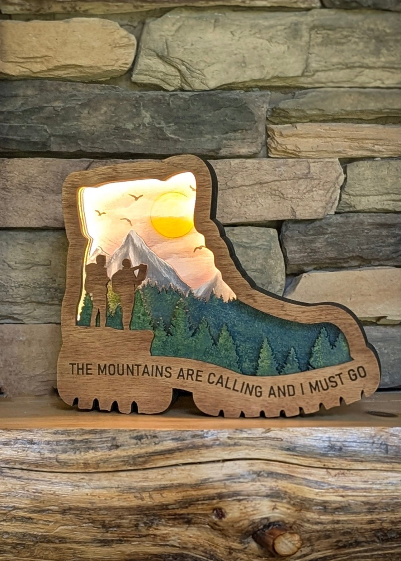 Hiking Boot "The Mountains Are Calling and I Must Go" Featured with the Light On displayed on a mantle