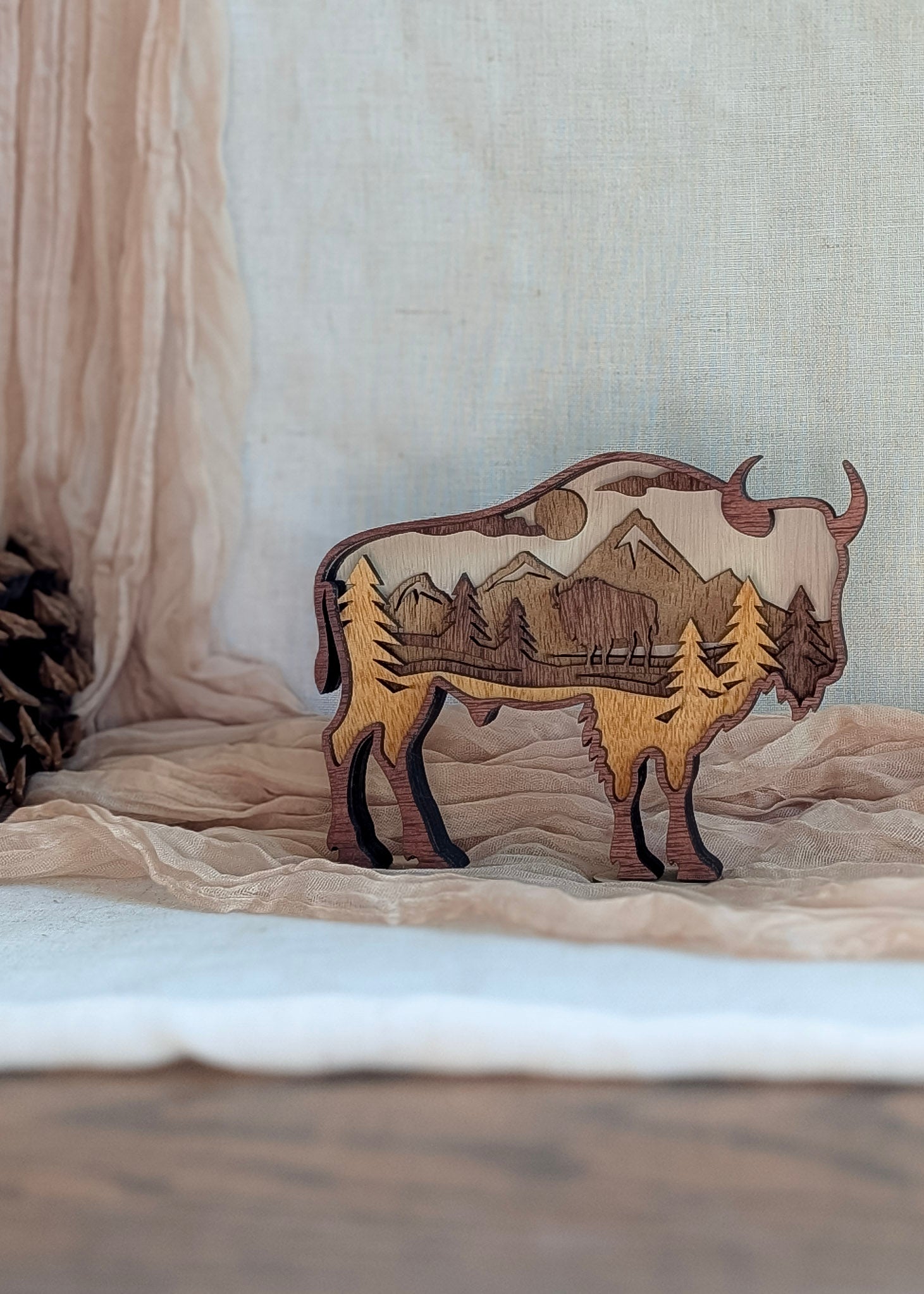 Natural wood tone bison silhouette with layered landscape and moonlit forest details.