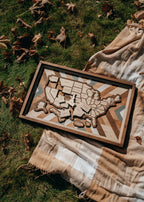 Overhead view of Heritage Quilt travel map laid on blanket outdoors, showcasing rustic tones and detailed wood grain