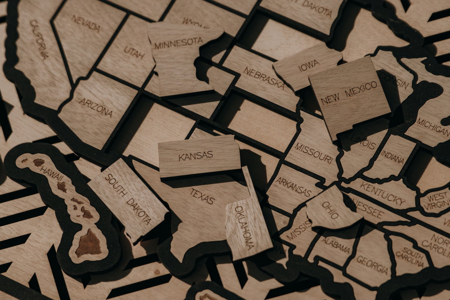 Detailed close-up of engraved wooden state pieces from the Hearthline Series USA travel map, handcrafted for tracking memories across all 50 states.