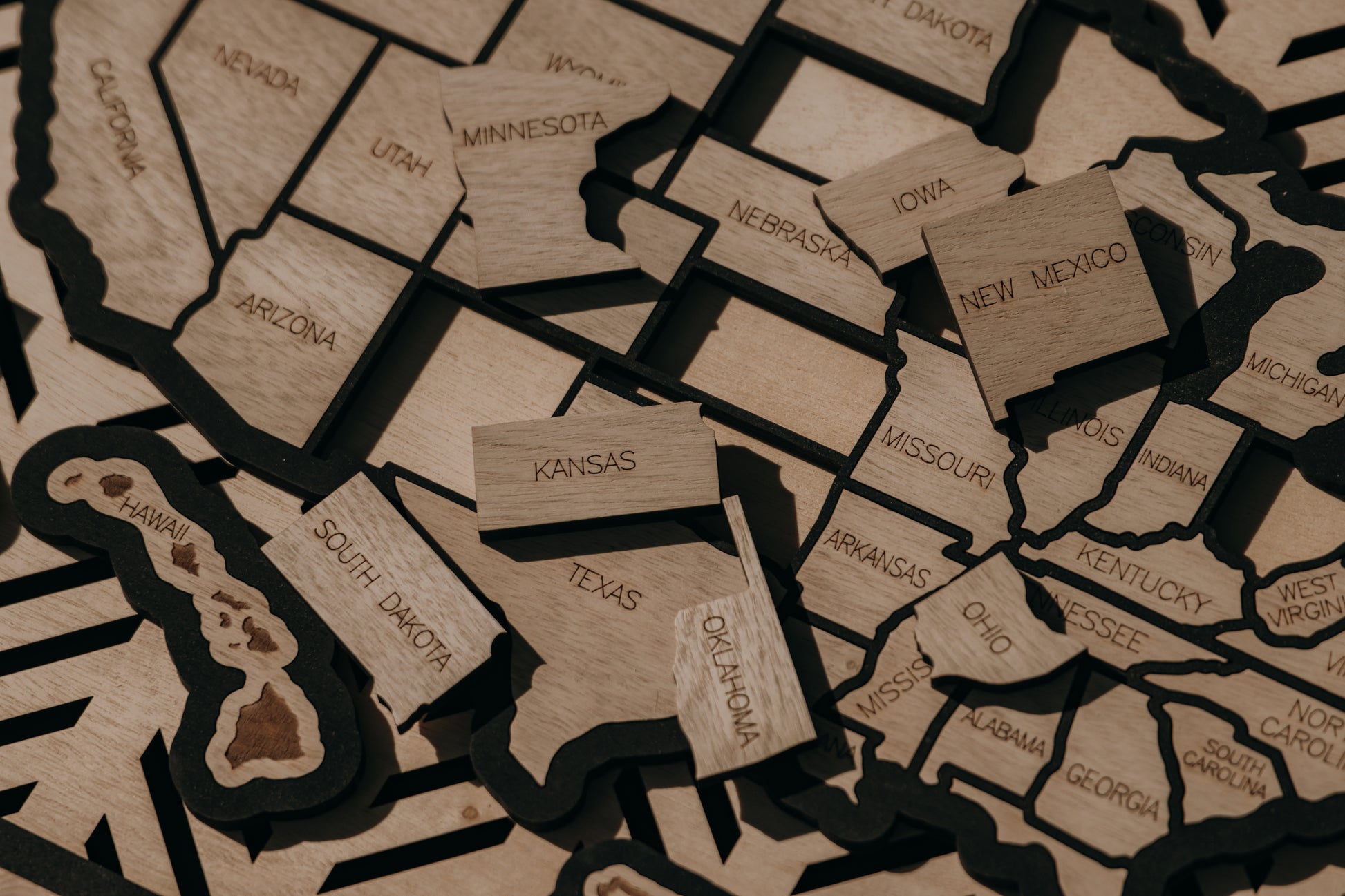 Detailed close-up of engraved wooden state pieces from the Hearthline Series USA travel map, handcrafted for tracking memories across all 50 states.