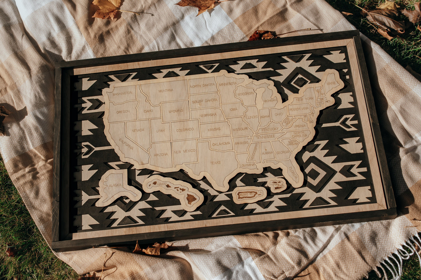 Handcrafted Heritage Trails wooden USA travel map from the Storyline Series displayed outdoors on a blanket with autumn leaves.