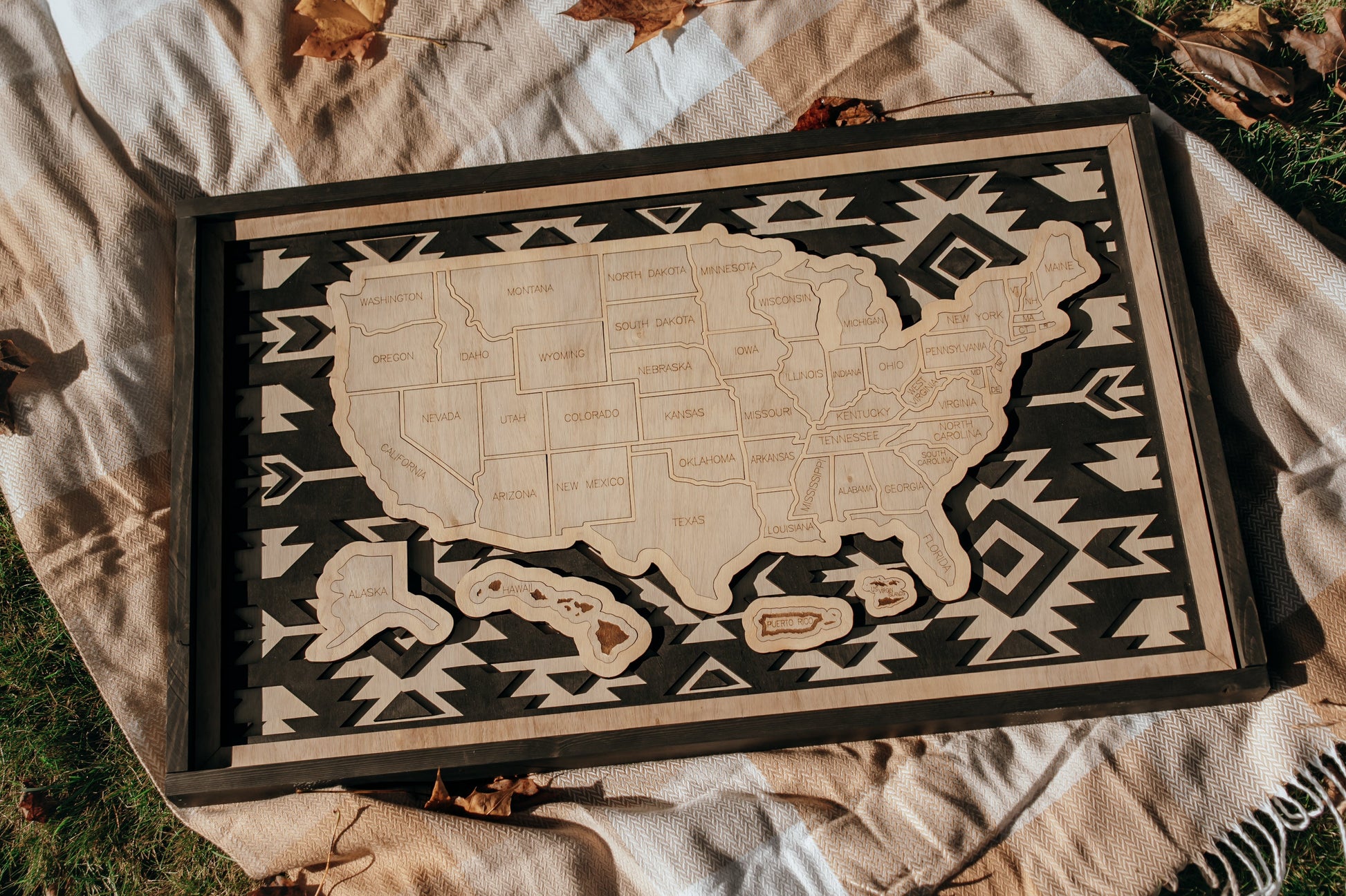 Handcrafted Heritage Trails wooden USA travel map from the Storyline Series displayed outdoors on a blanket with autumn leaves.