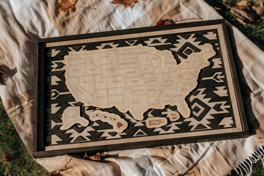 Handcrafted Heritage Trails wooden USA travel map from the Storyline Series displayed outdoors on a blanket with autumn leaves.