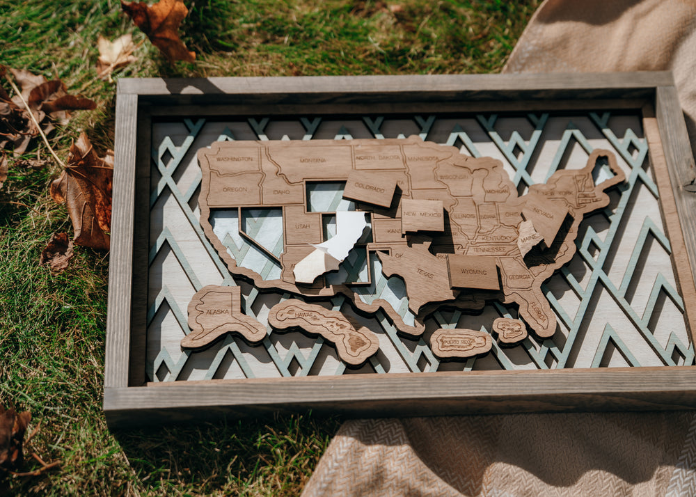 Close-up of peel-and-stick wooden state pieces being added to the Summit Peaks travel map.