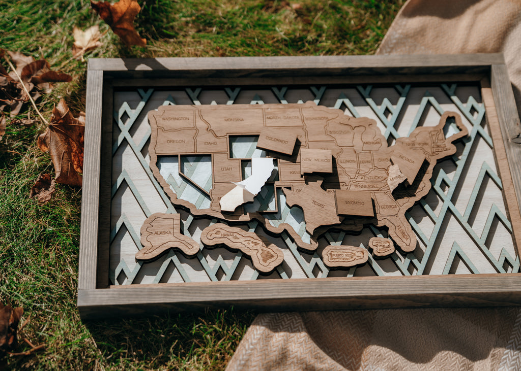 Close-up of peel-and-stick wooden state pieces being added to the Summit Peaks travel map.