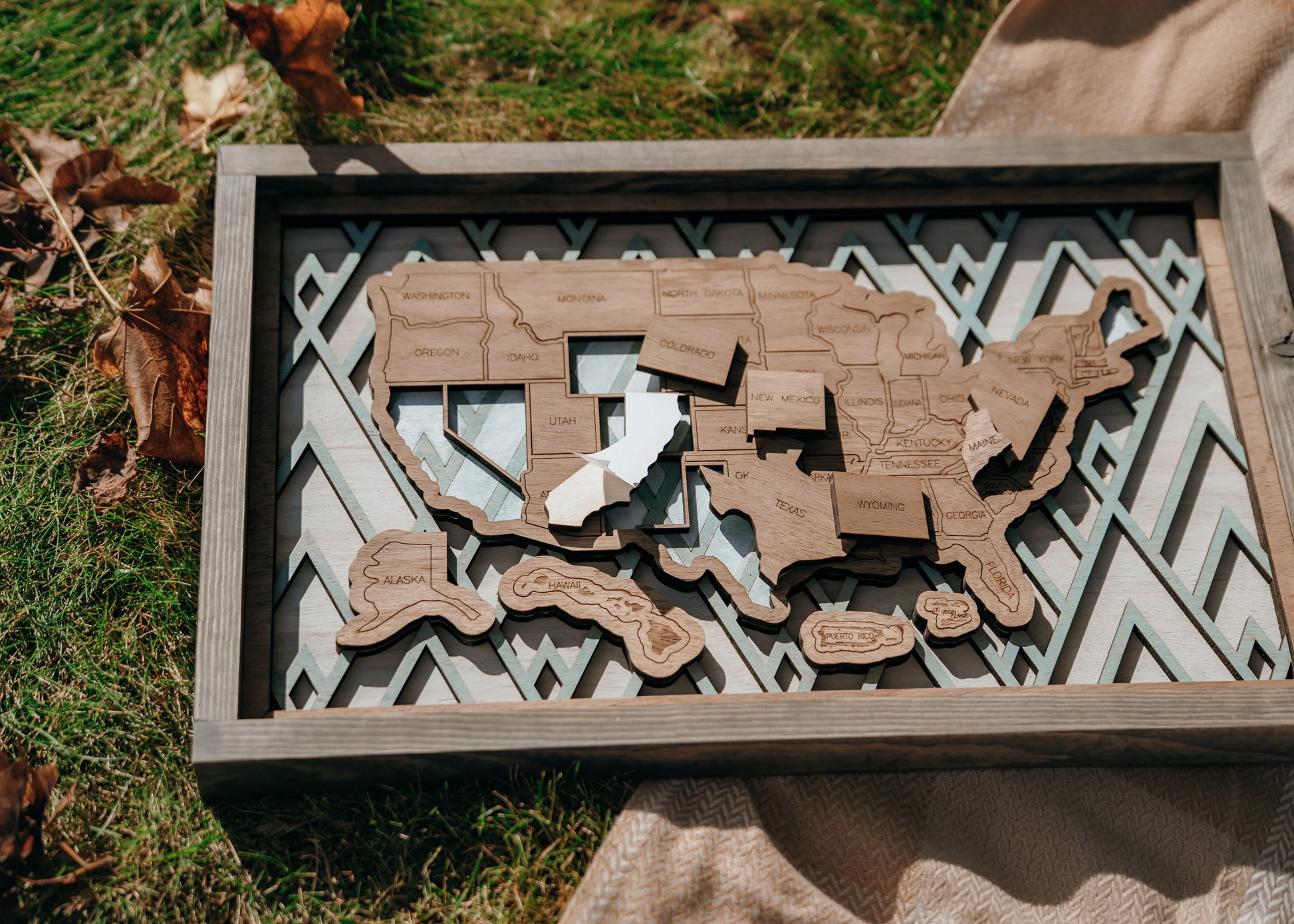 Close-up of peel-and-stick wooden state pieces being added to the Summit Peaks travel map.