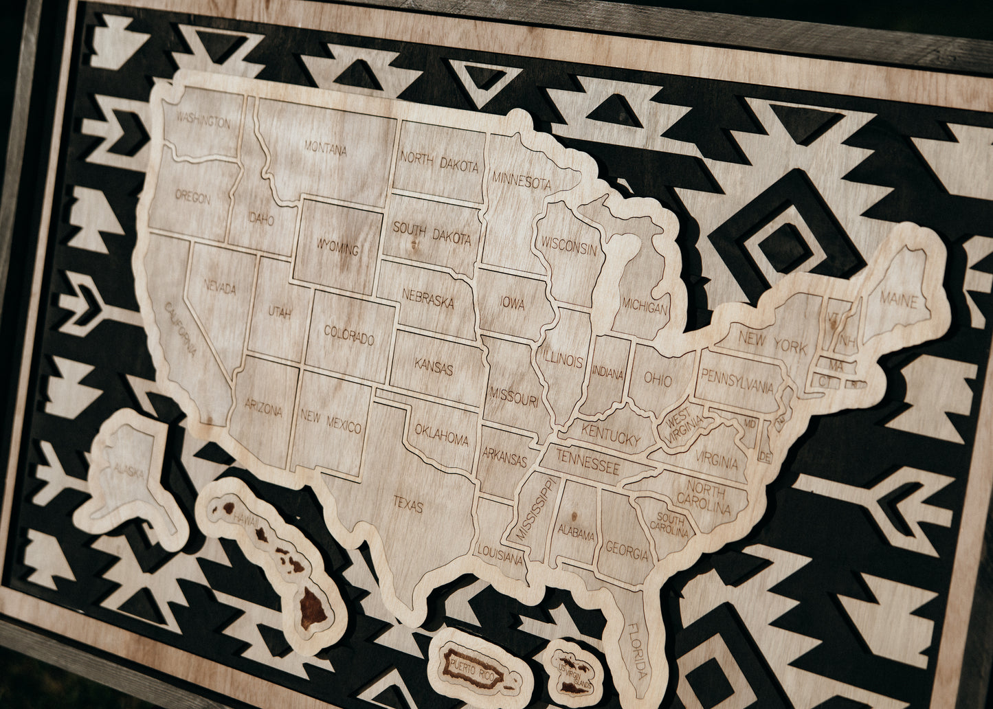Detailed view of a handcrafted wooden USA travel map from the Storyline Series, featuring engraved states and bold geometric background.